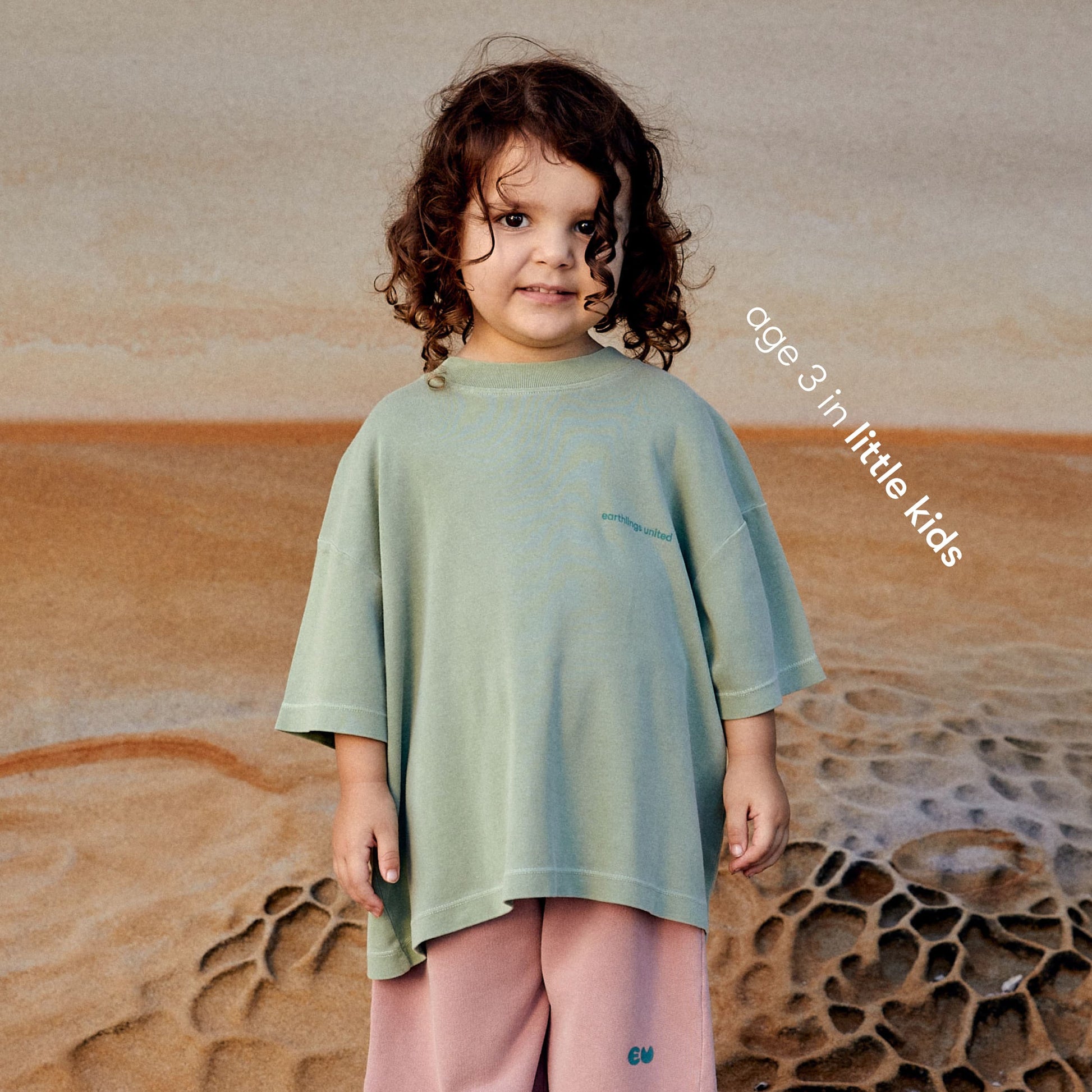 Young girl wearing a sustainable green kids' T-shirt by Earthlings United, made from soft organic cotton for durability and comfort