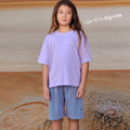 Young girl wearing a sustainable  purple kids' T-shirt by Earthlings United, made from soft organic cotton for durability and comfort