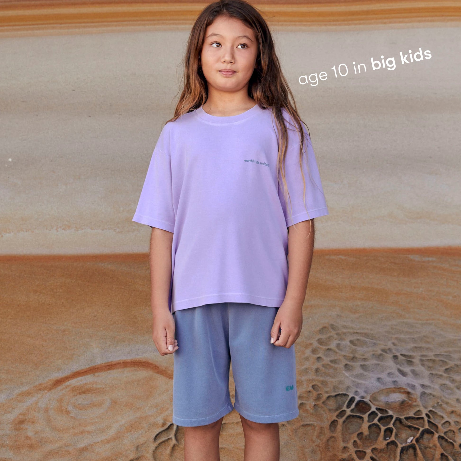 Young girl wearing a sustainable  purple kids' T-shirt by Earthlings United, made from soft organic cotton for durability and comfort