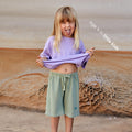 Young girl wearing a sustainable green kids' shorts by Earthlings United, made from soft organic cotton for comfort and durability