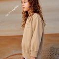 Young girl wearing a sustainable brown kids' jumper by Earthlings United, made from soft organic cotton for comfort and durability