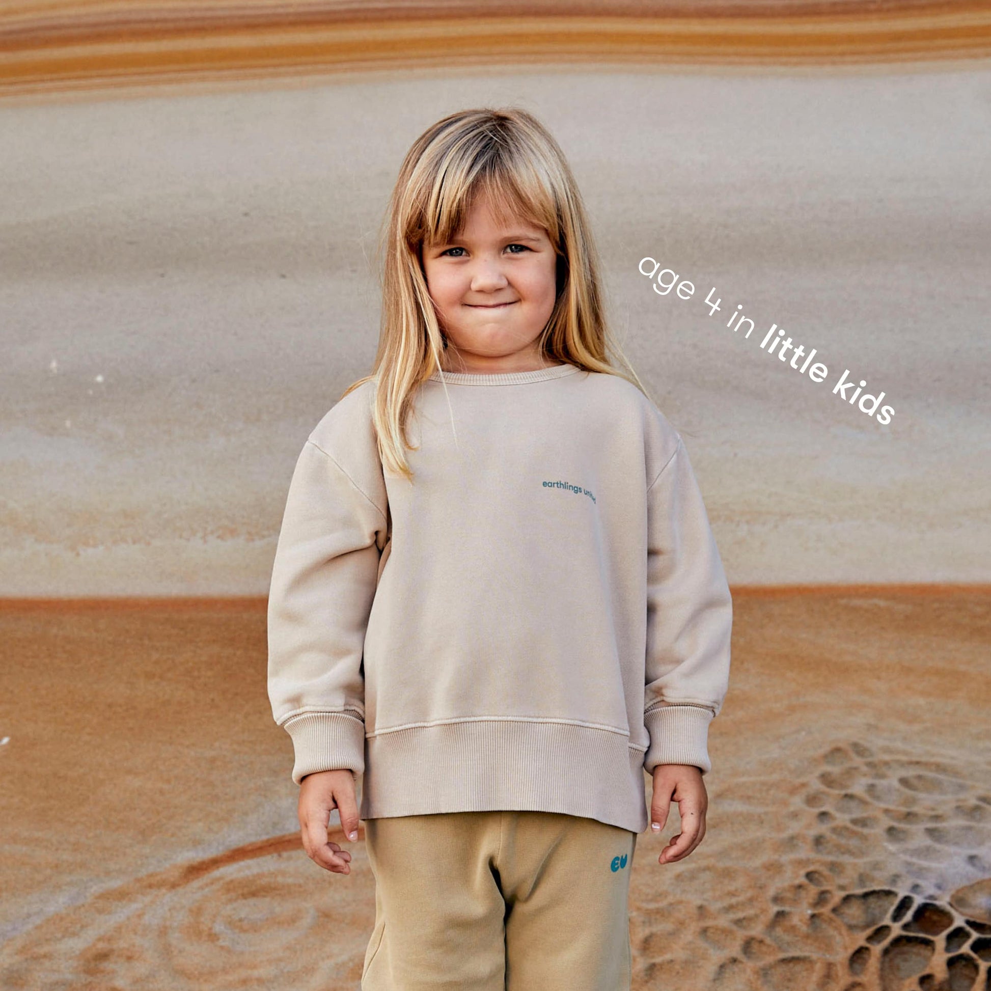 Young girl wearing a sustainable cream kids' jumper by Earthlings United, made from soft organic cotton for comfort and durability