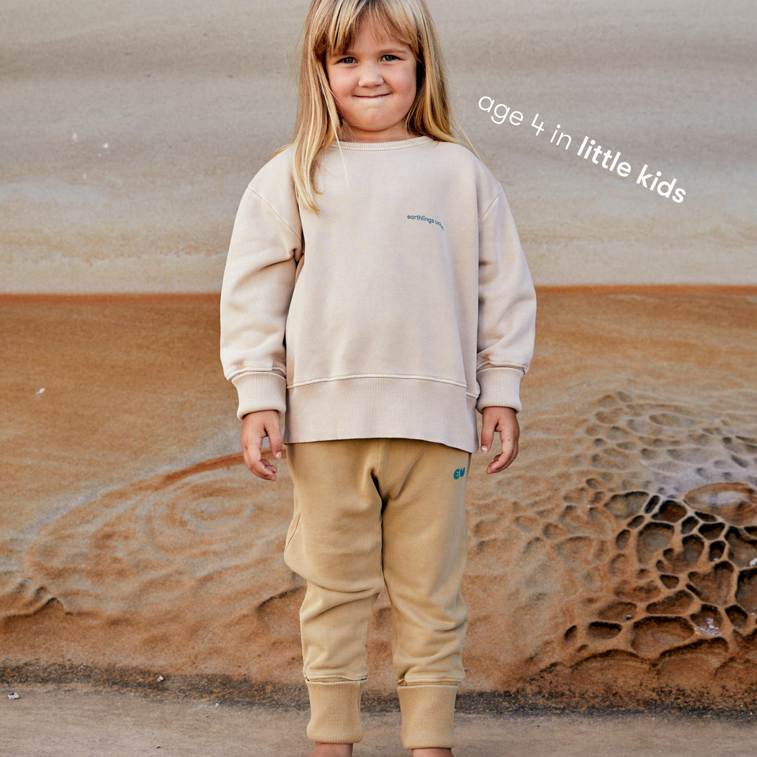 Young girl wearing a sustainable cream kids' jumper by Earthlings United, made from soft organic cotton for comfort and durability