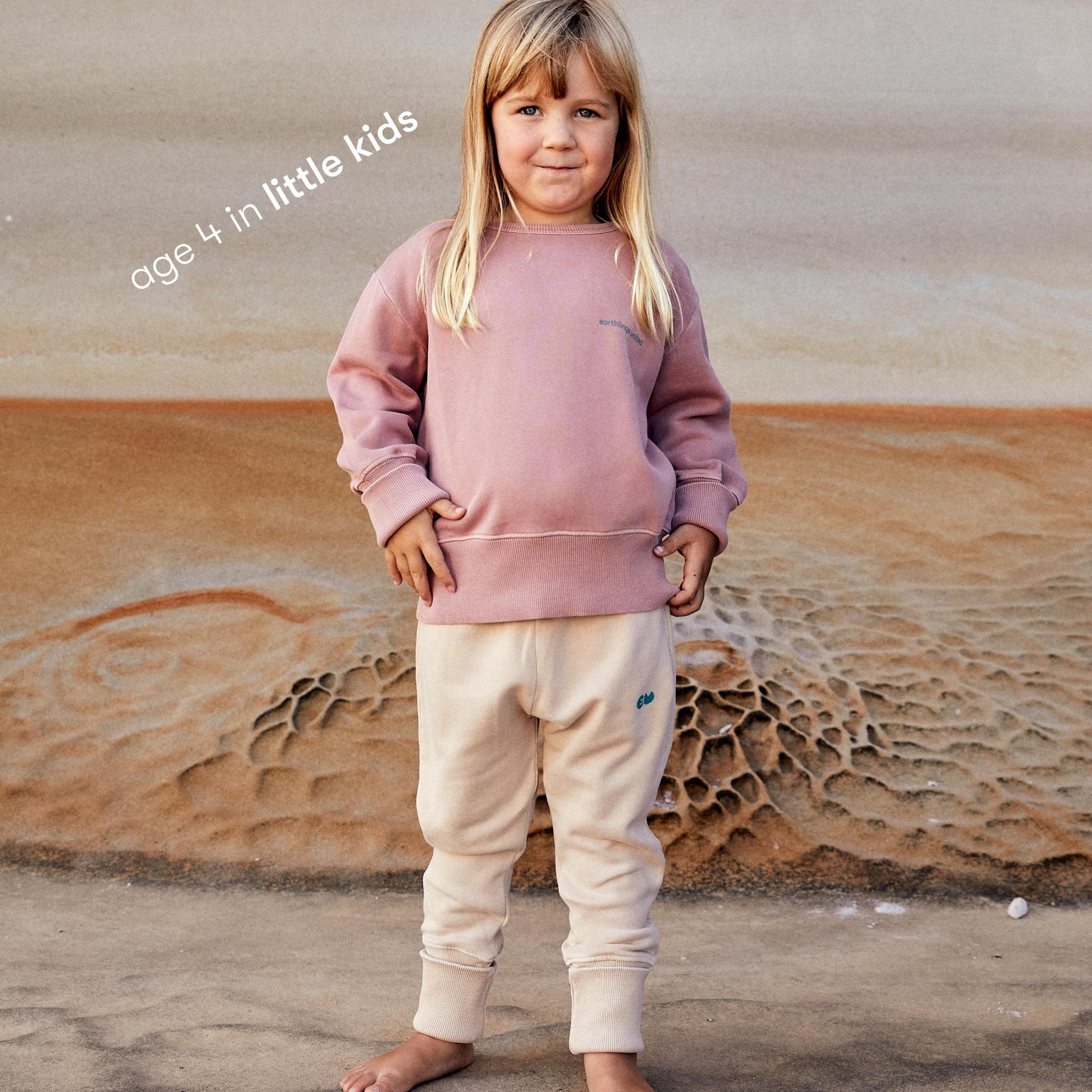 Young girl wearing a sustainable red kids' jumper by Earthlings United, made from soft organic cotton for comfort and durability