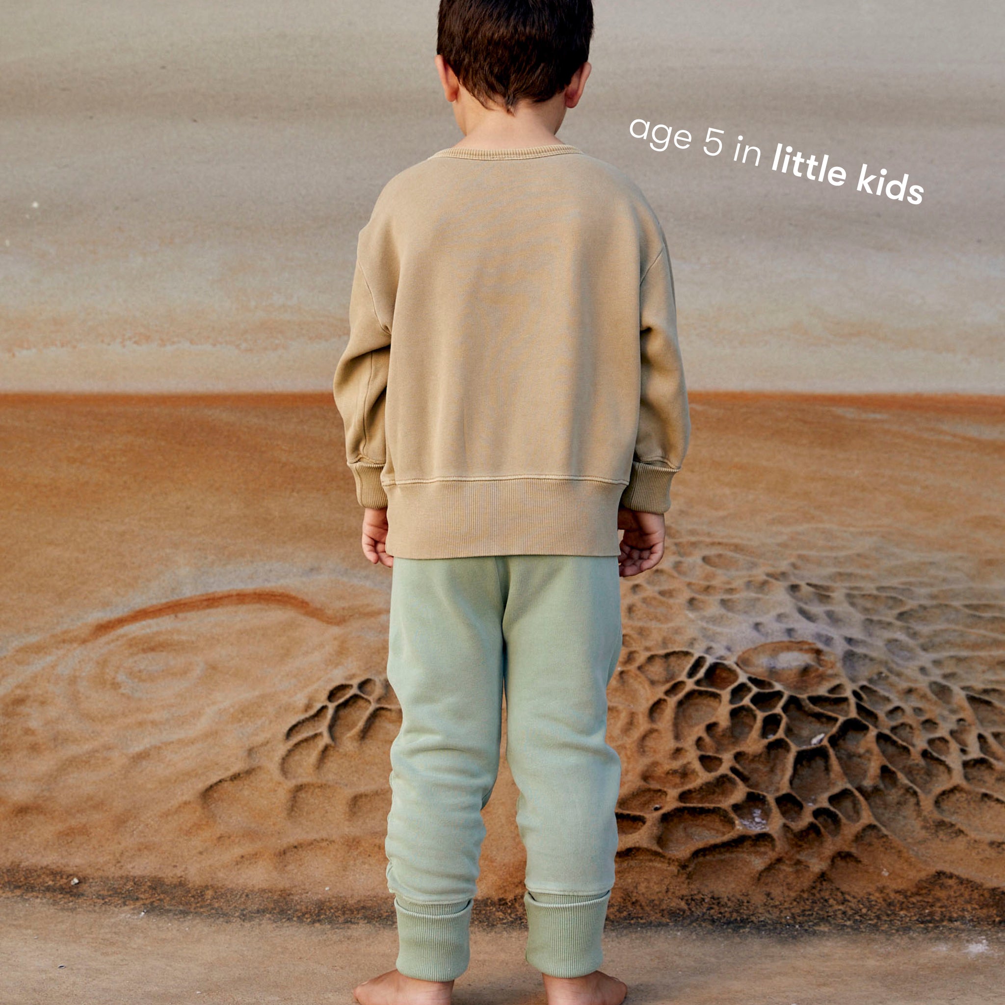 Young boy wearing a sustainable green kids' trackpants by Earthlings United, made from soft organic cotton for comfort and durability